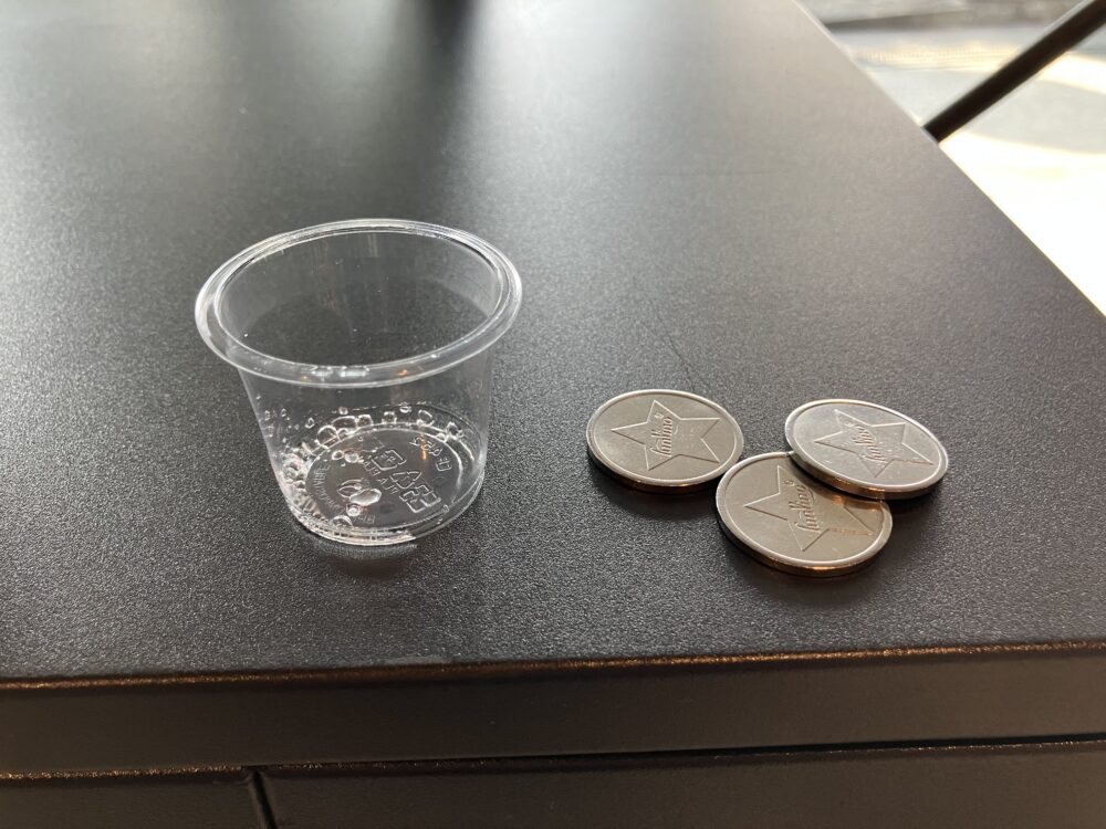 試飲用カップとコイン3枚の写真